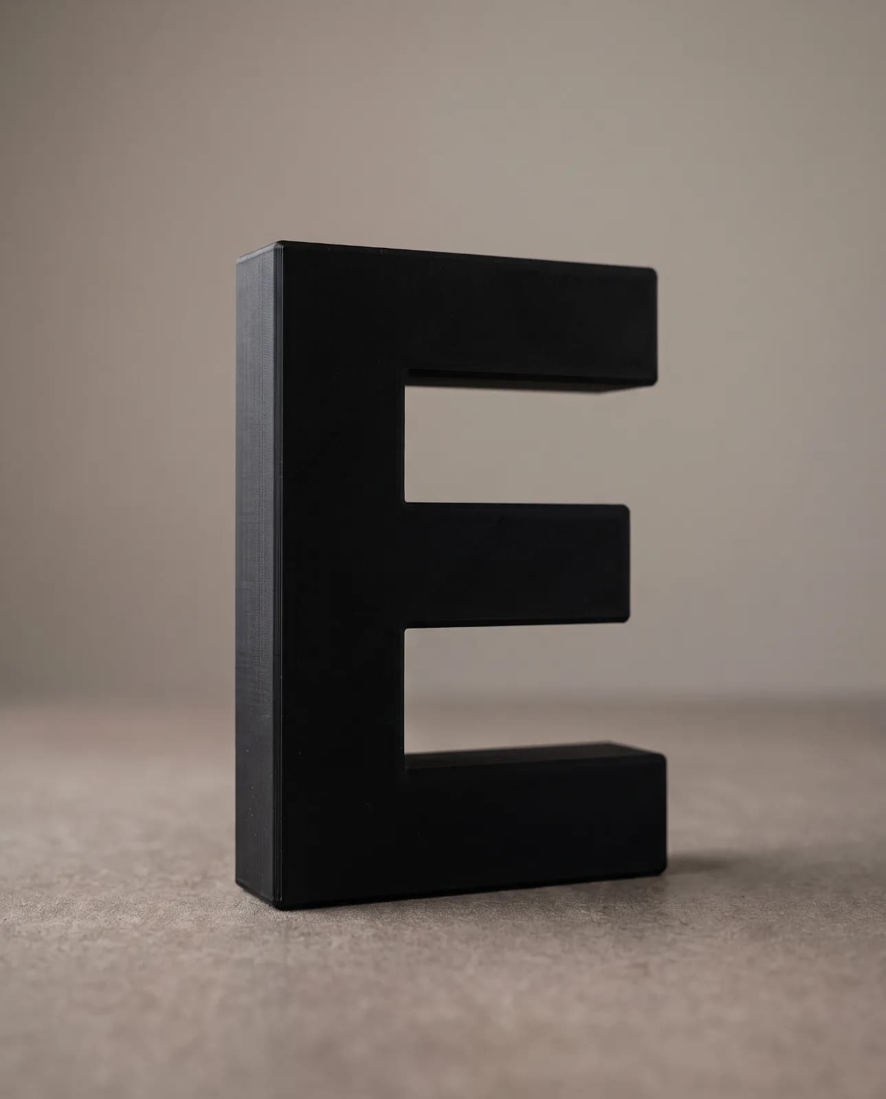 A matte black 3D-printed letter E with no reflections