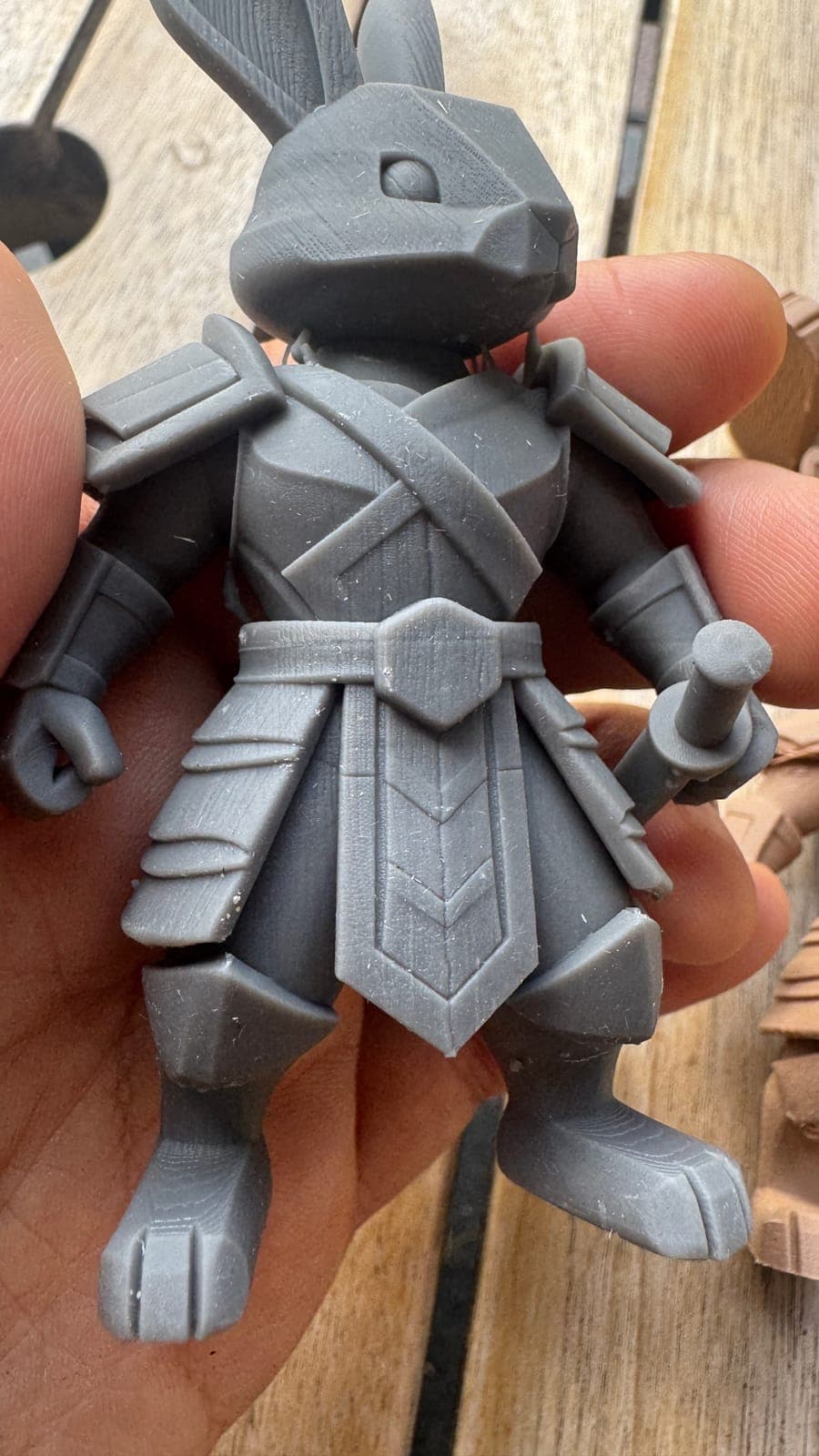 An unpainted resin print of an armoured rabbit warrior, held in the hand