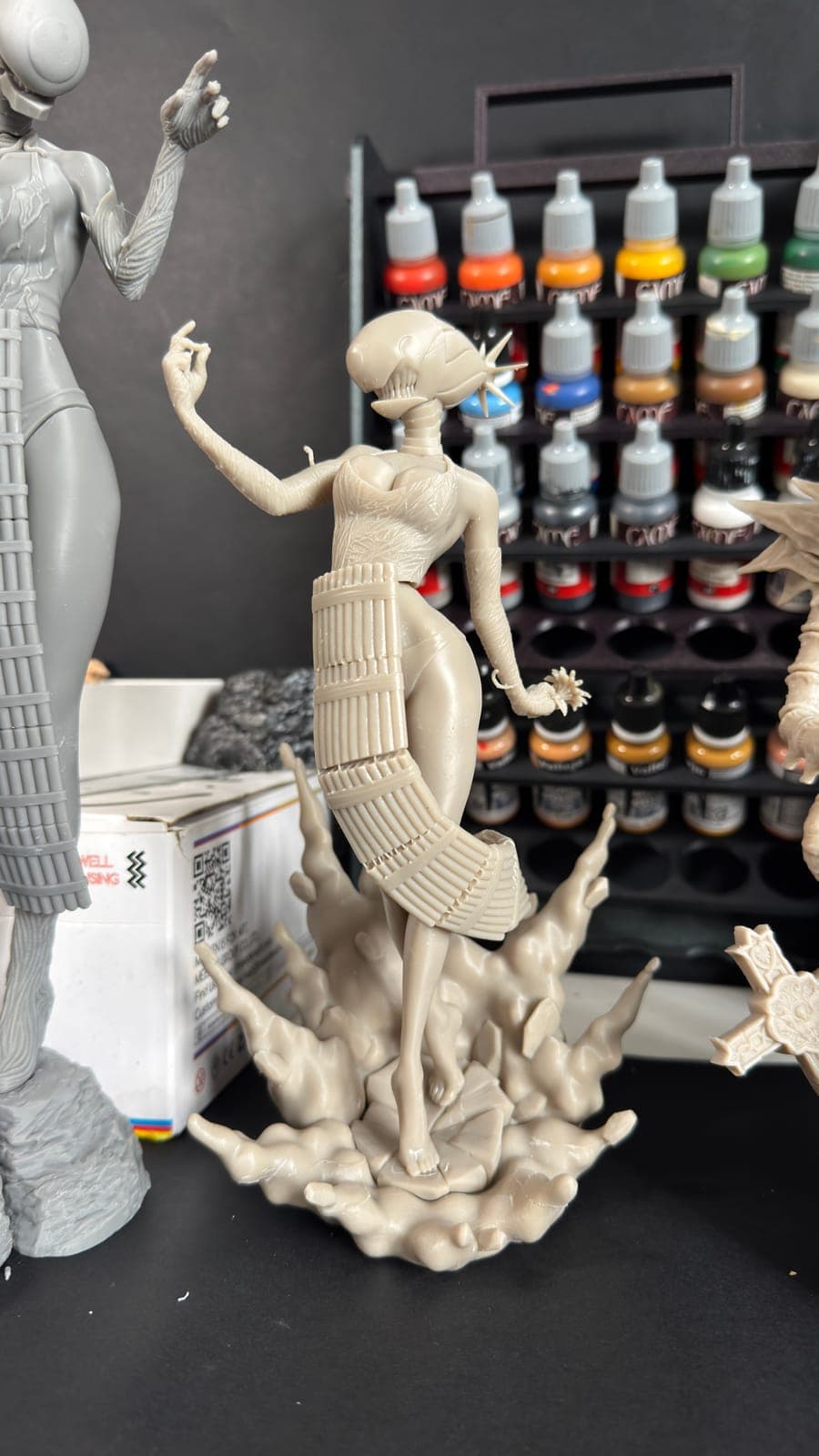 Unpainted resin figures in front of the studio paint rack