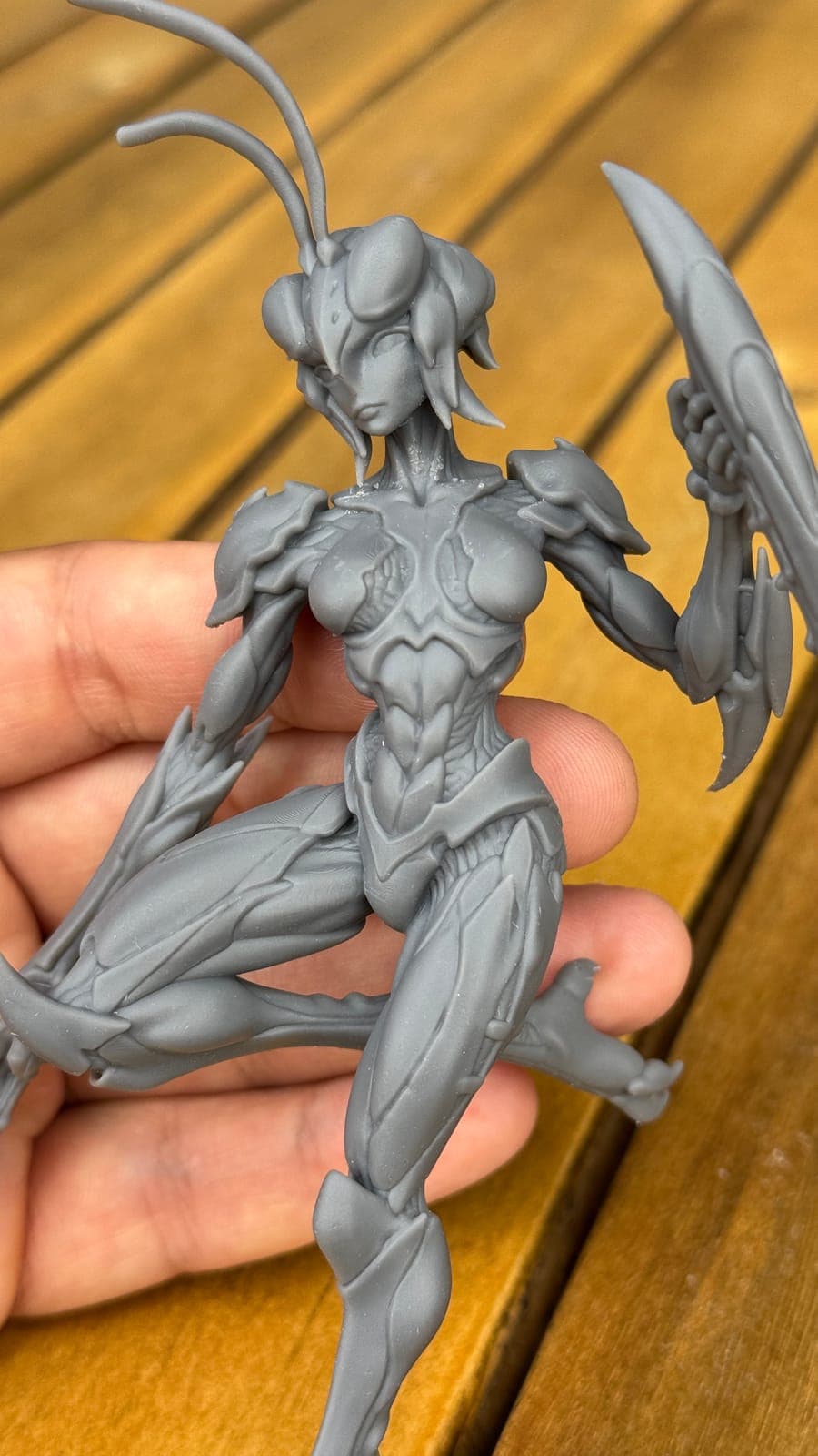 The unpainted insect warrior print held over a wooden table