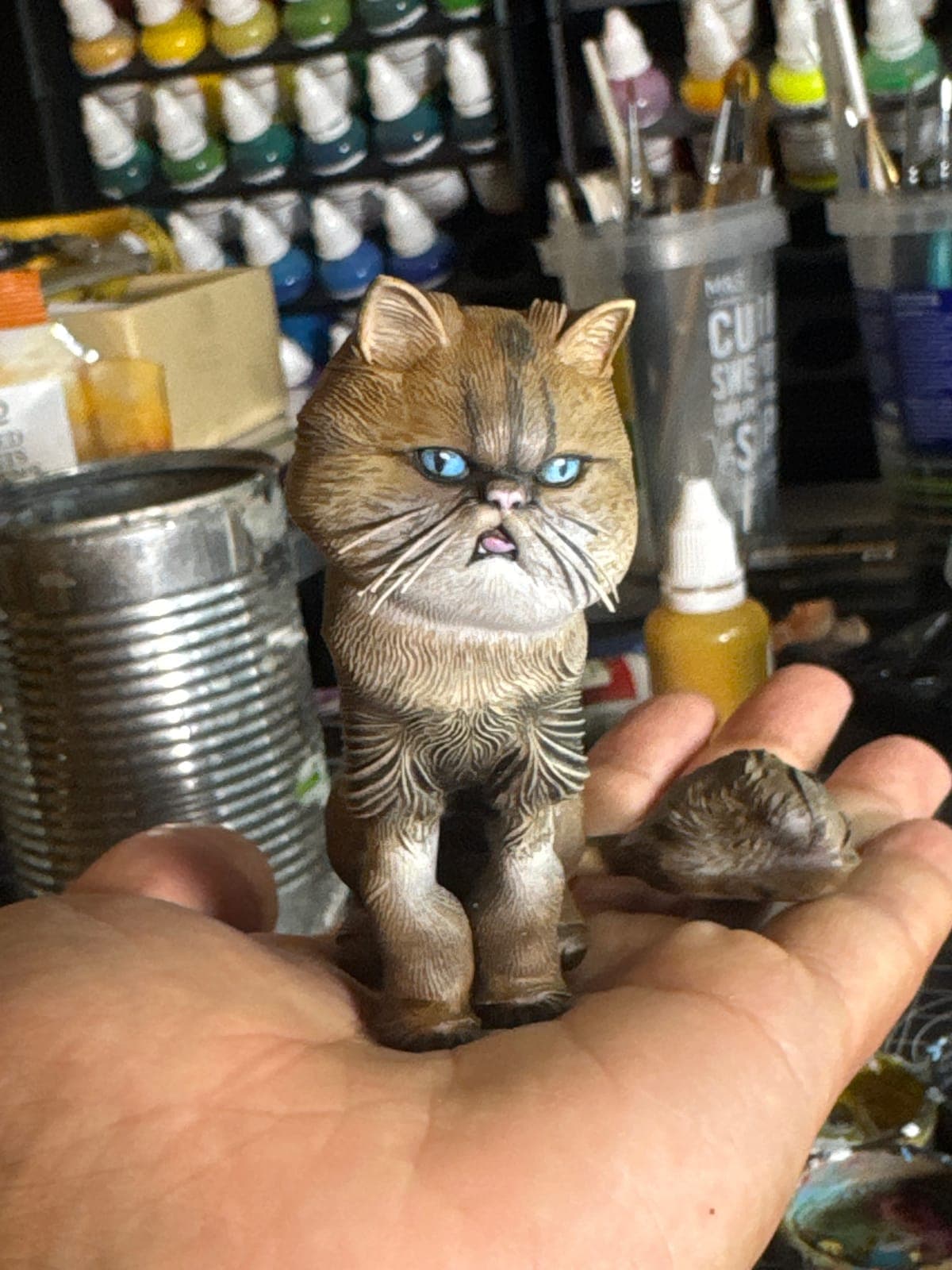 A hand-painted Persian cat figurine held in the palm