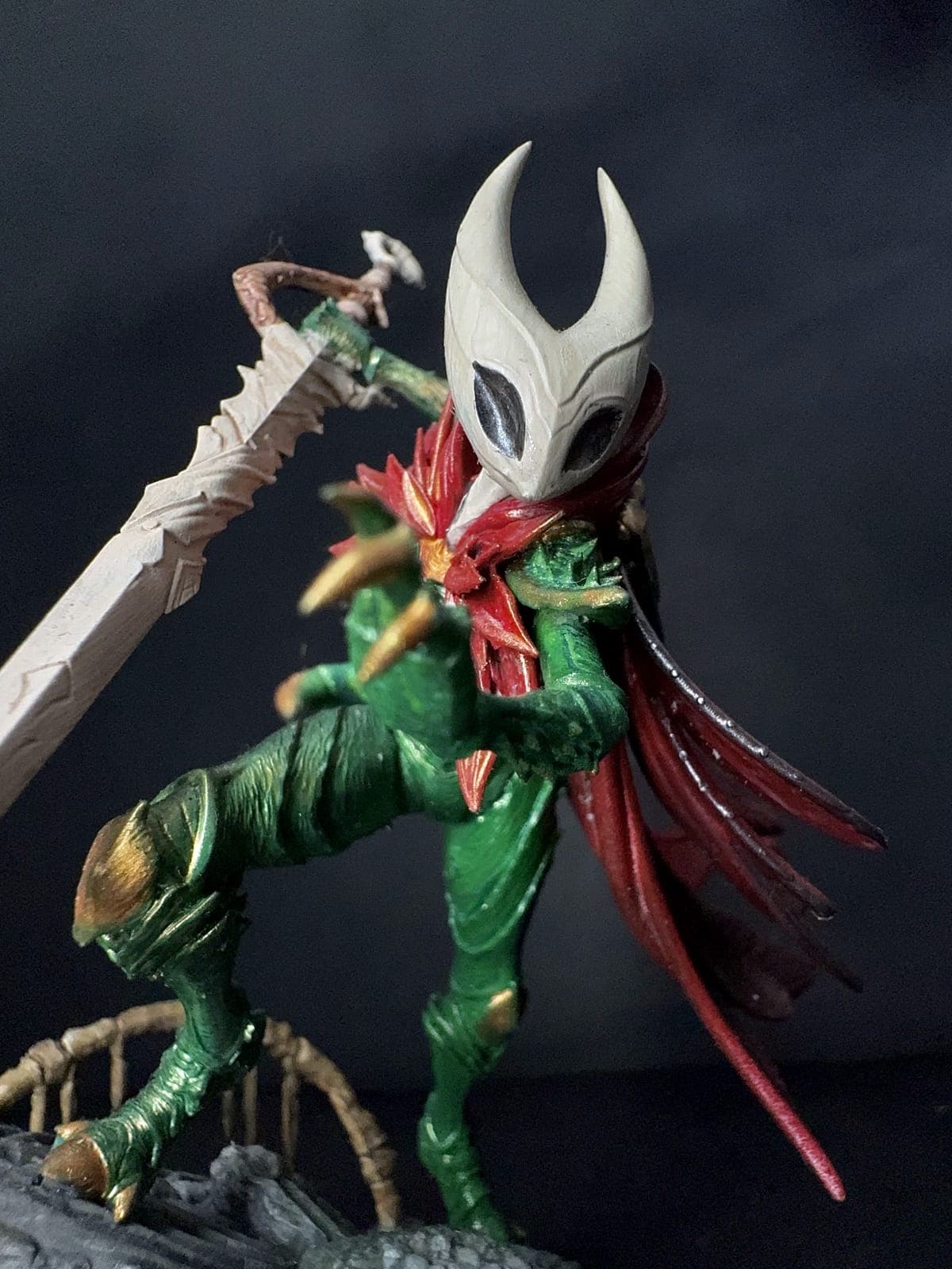 A hand-painted resin figure of a masked warrior with a red cloak and a needle sword