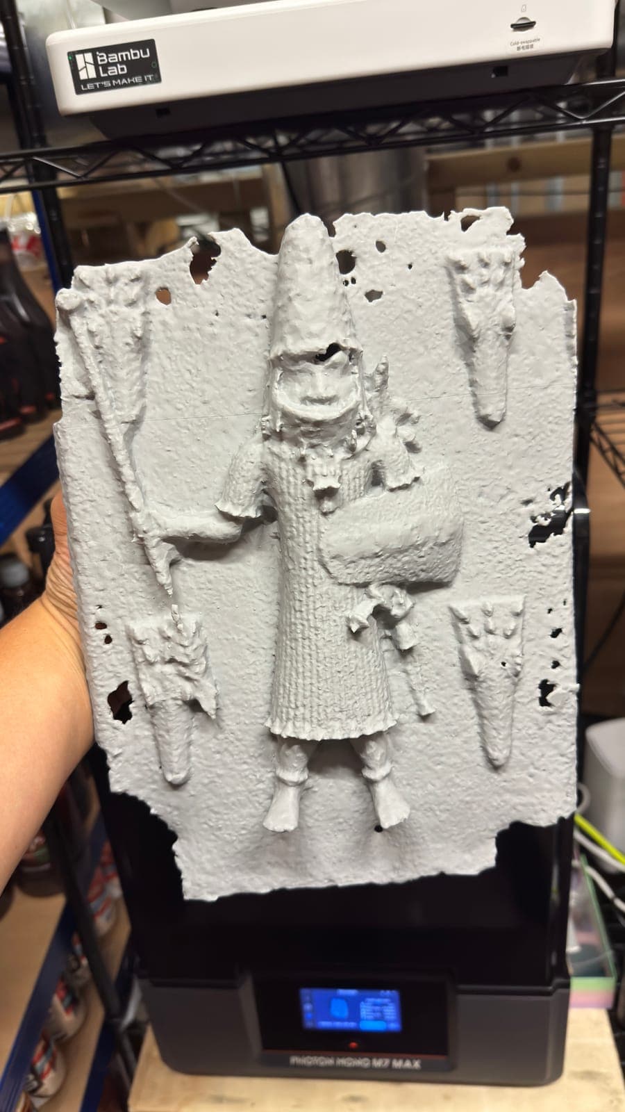 An unpainted resin relief panel resting on top of the resin printer