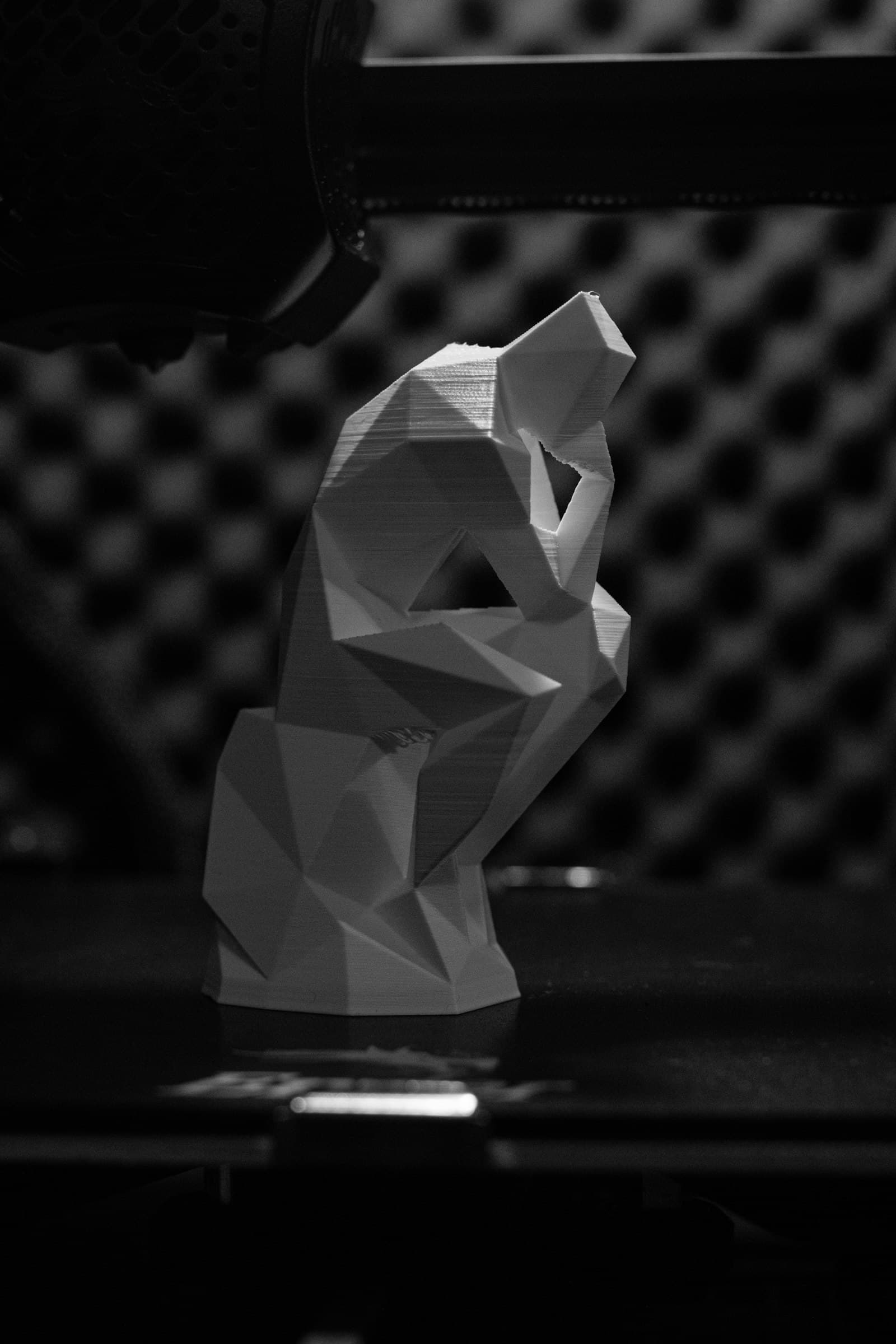 A white 3D-printed low-poly figure on a dark background