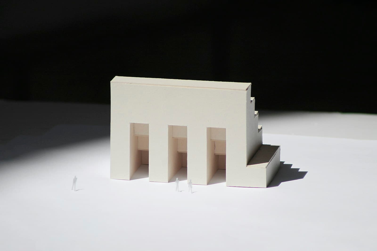 A white architectural model with tiny scale figures beside it