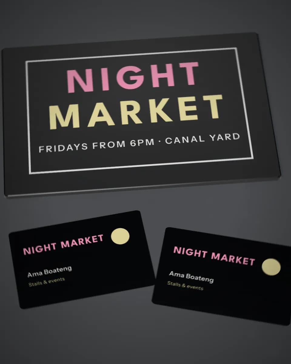 A black sign and business cards printed in white ink with fluorescent pink and yellow lettering