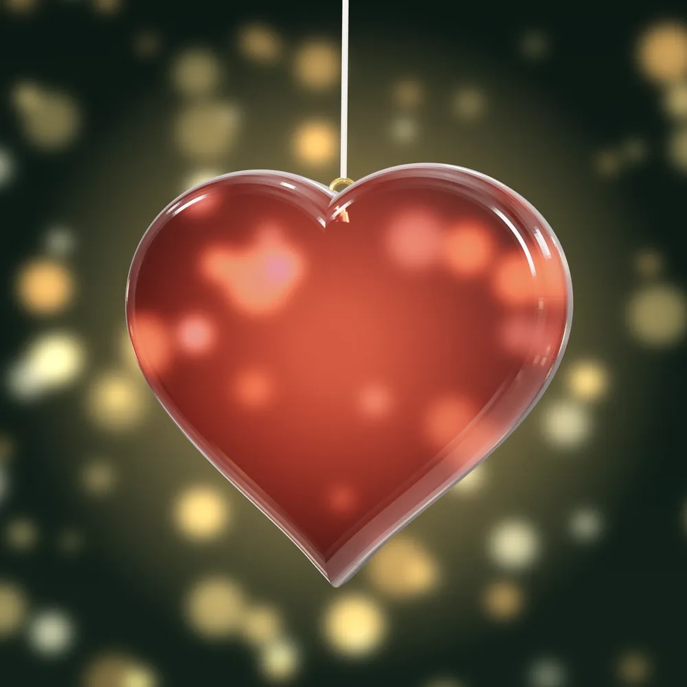 A rose-tinted, glass-like heart bauble lit from behind by warm lights