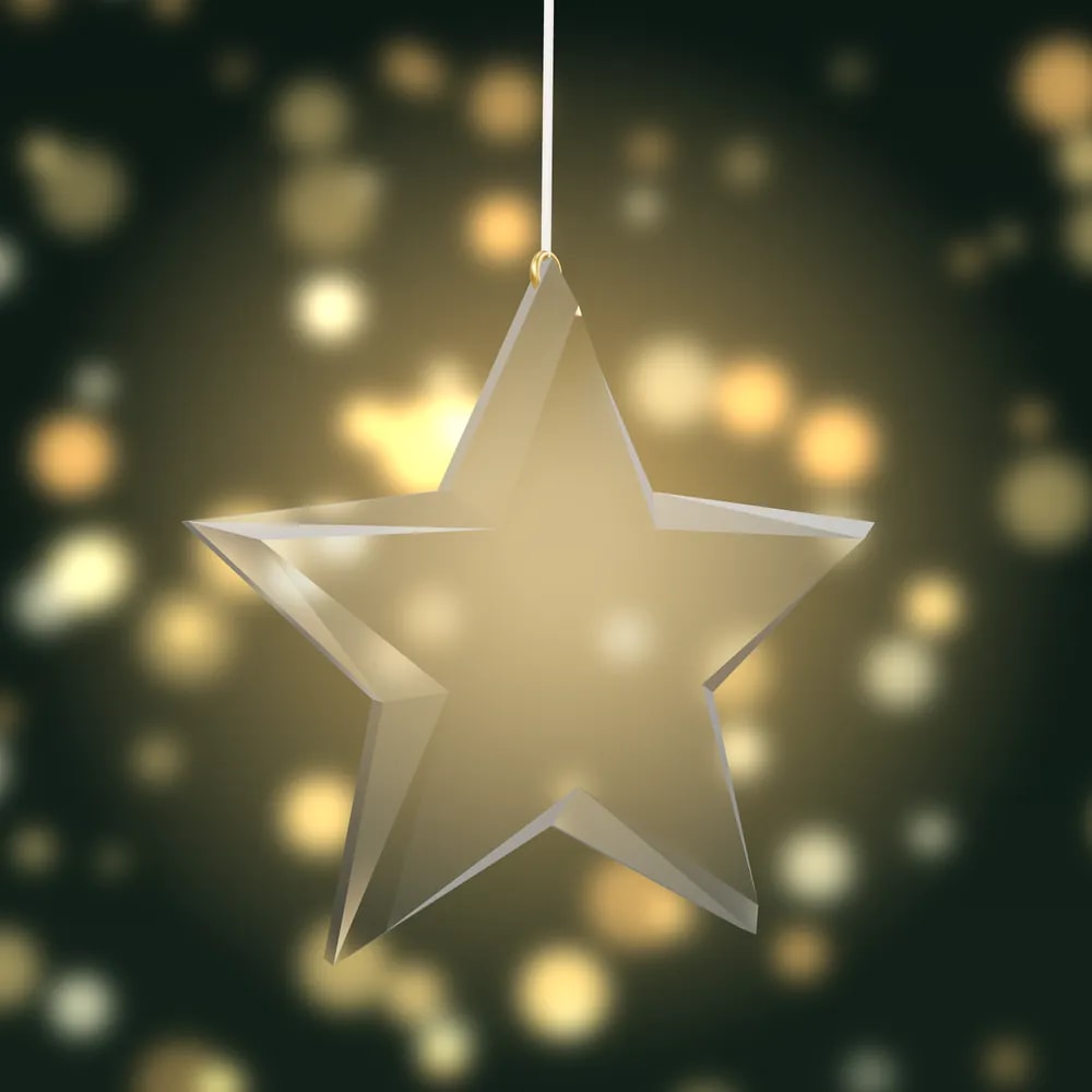 A clear, faceted star bauble with a pale gold tint, lit from behind