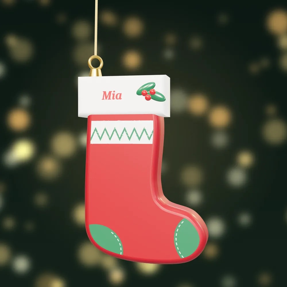 A hand-painted red Christmas stocking bauble with a white cuff painted with the name Mia and a sprig of holly