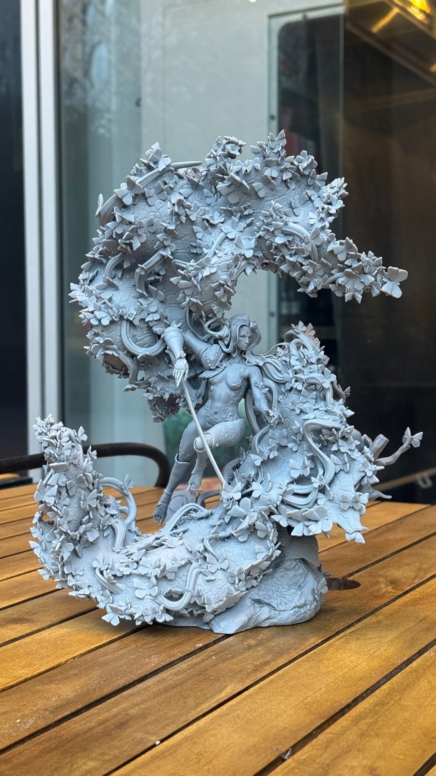 A large unpainted resin diorama of swirling leaves around a figure, on the studio table
