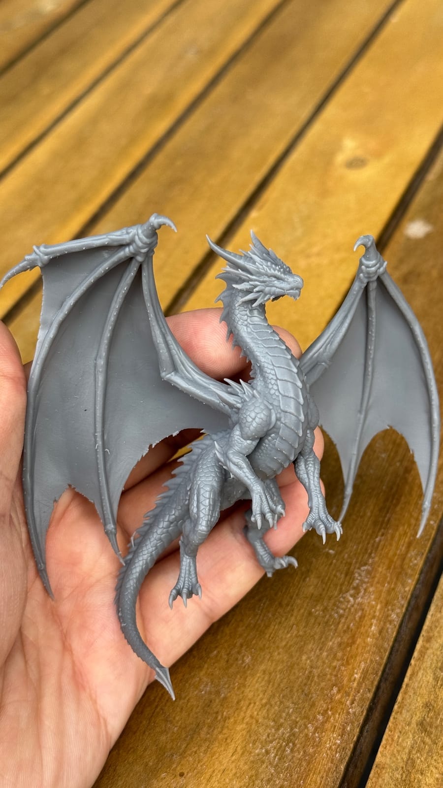 An unpainted resin print of a winged dragon, held in the hand
