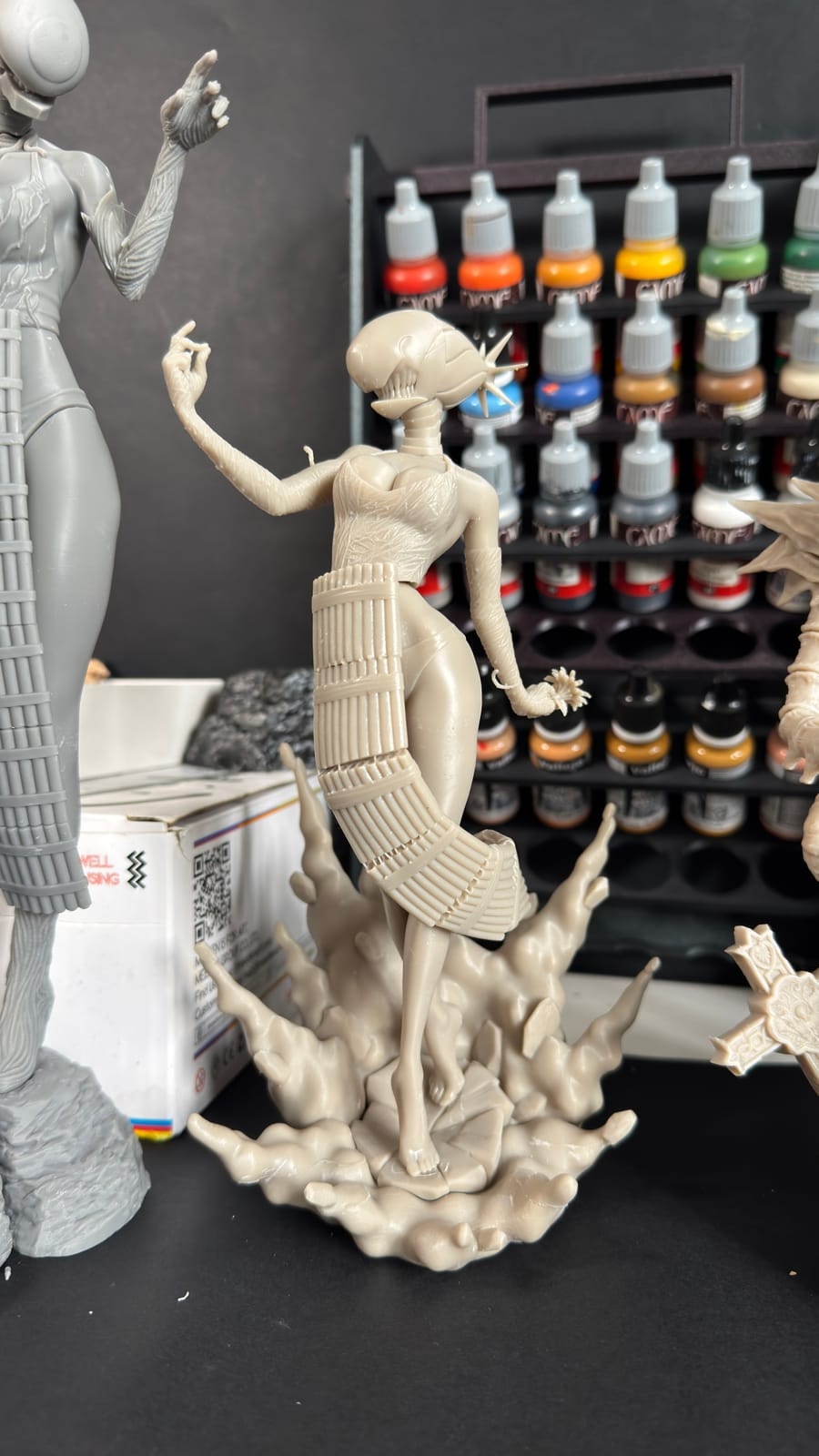 Unpainted resin figures in front of the studio paint rack