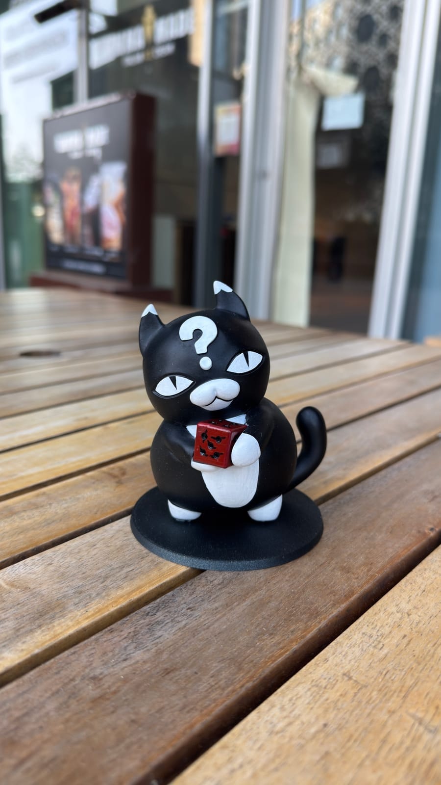 The painted question-mark cat on its black base in the studio window