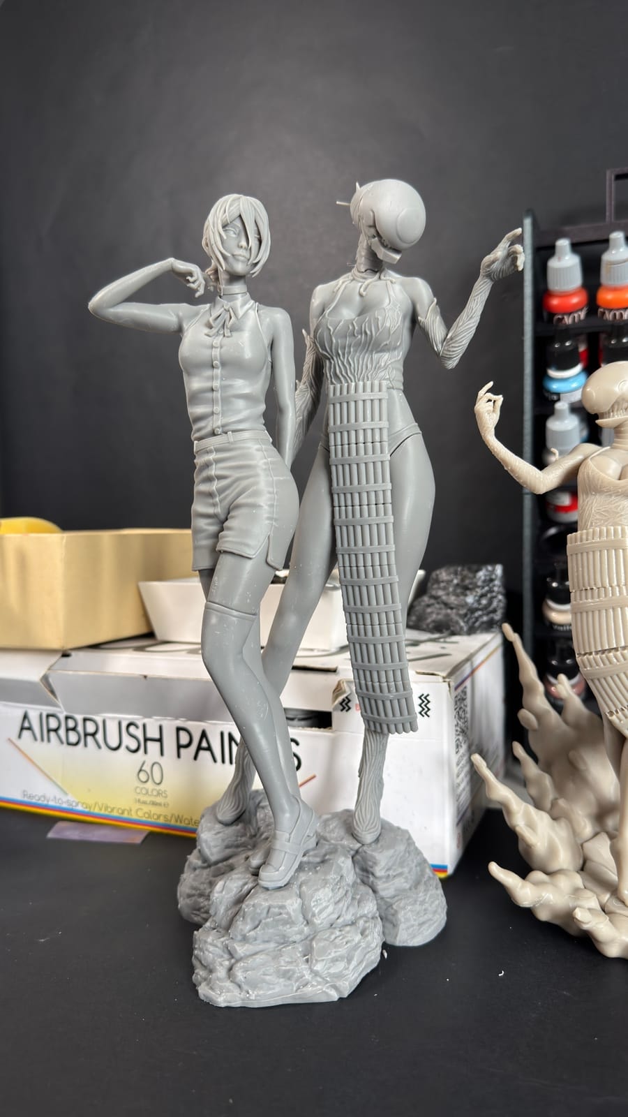 Tall unpainted resin figures standing on the workbench