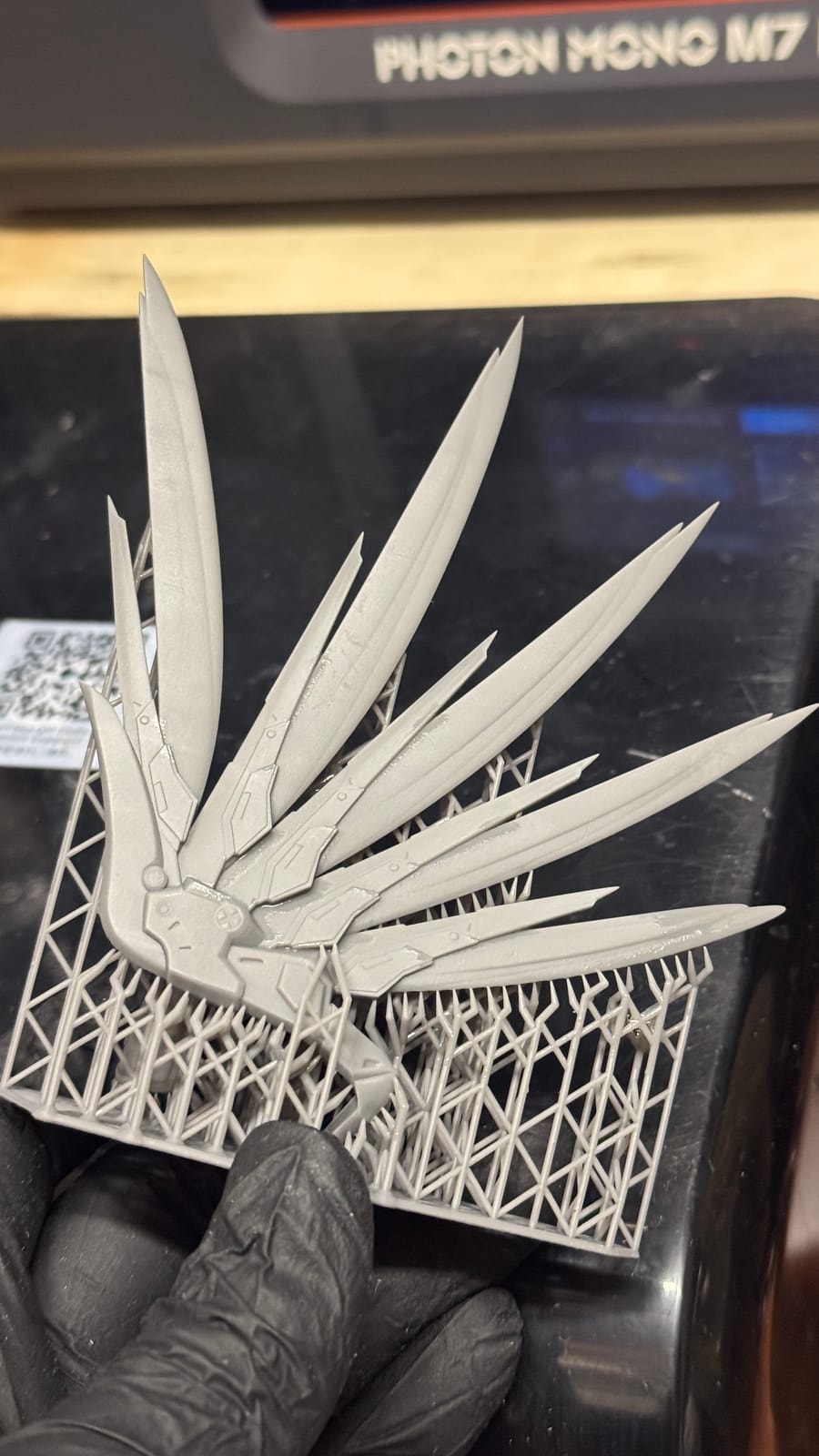 Freshly printed resin wings still on their supports, held above a Photon Mono M7 build plate
