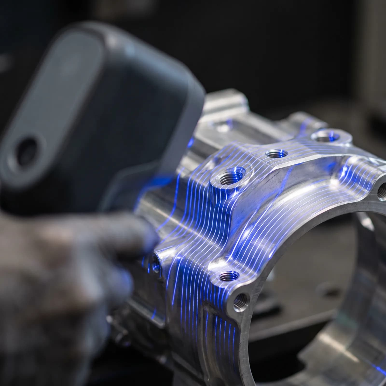 Close-up of blue laser lines tracing the edges of a machined metal part