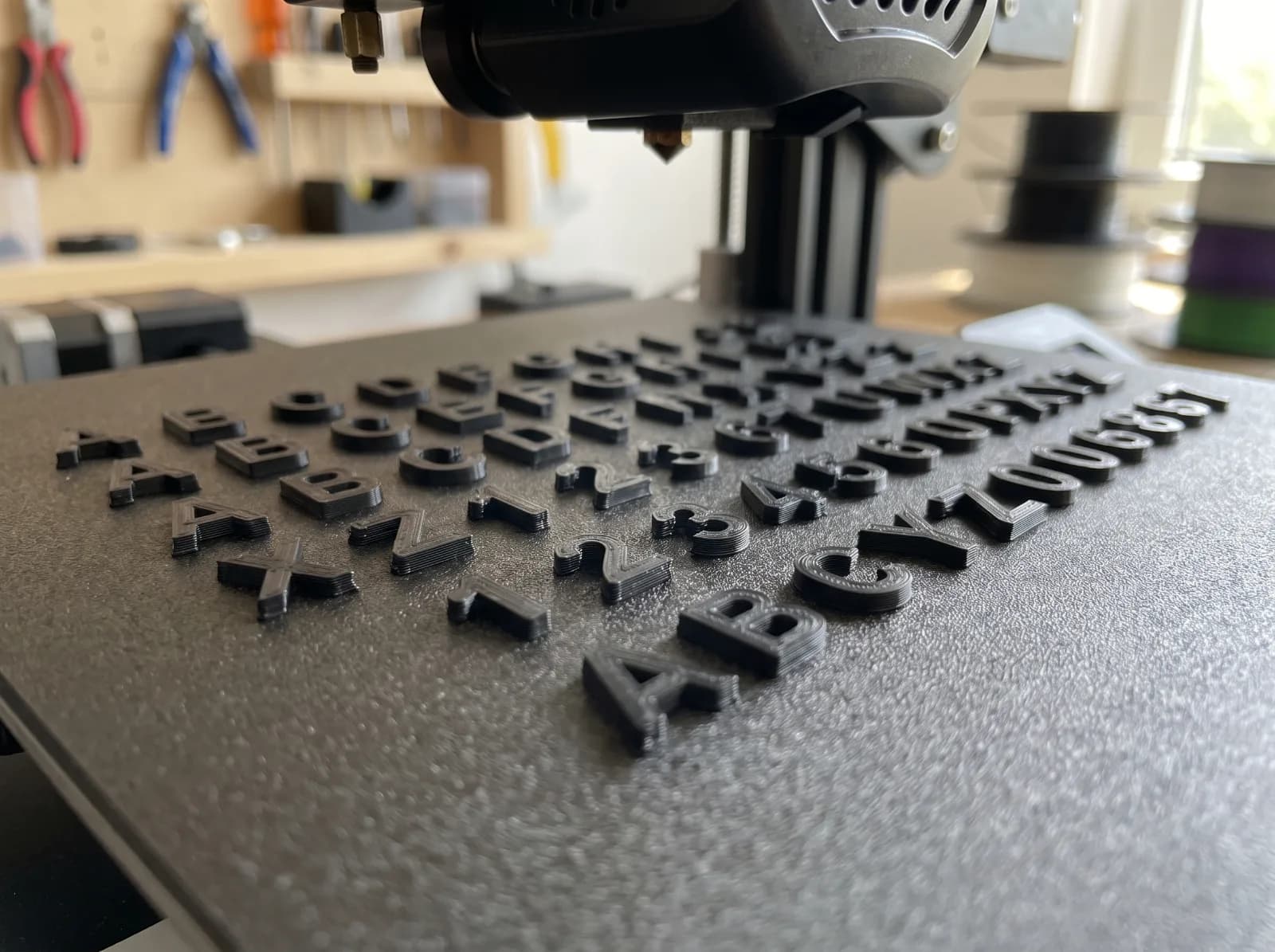 Rows of black letters and numbers freshly 3D printed on a printer's build plate