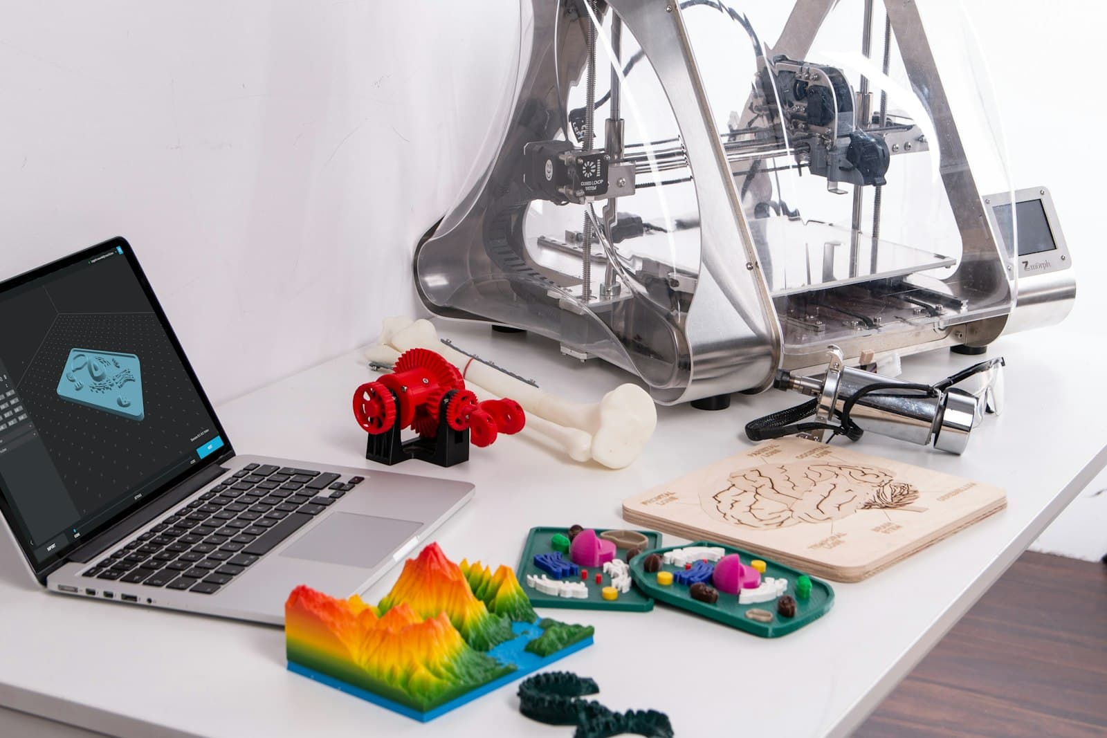 A 3D printer beside a laptop and printed pieces