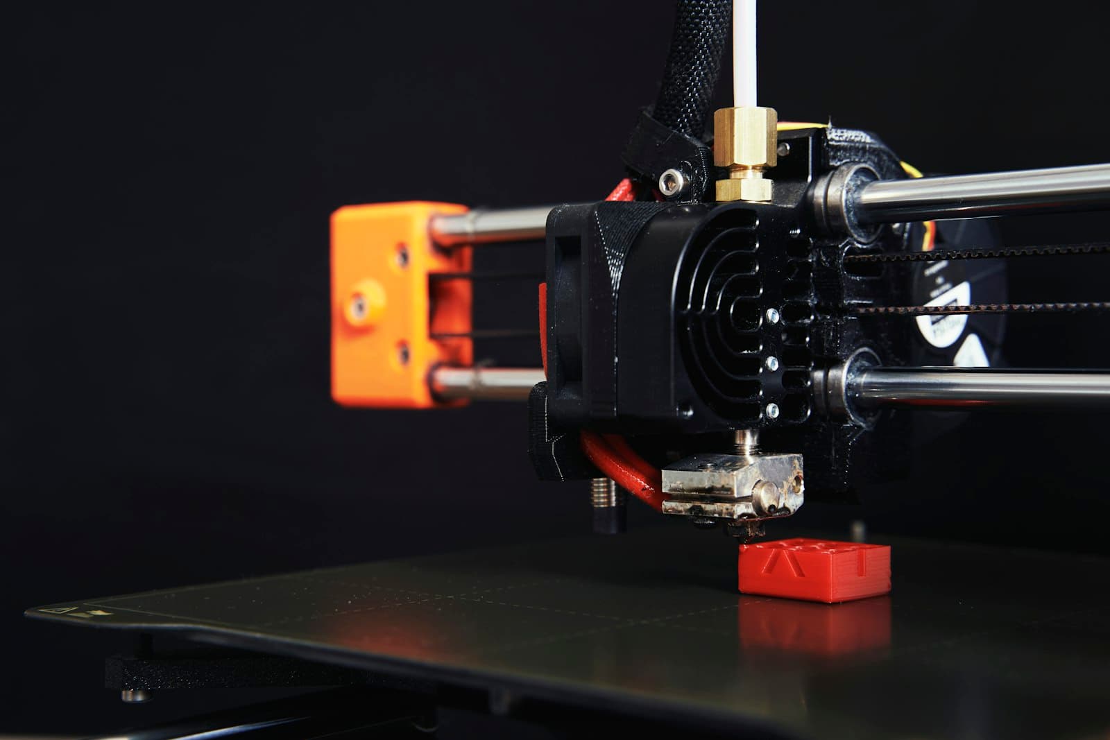 Close-up of an FDM hotend printing a small red part
