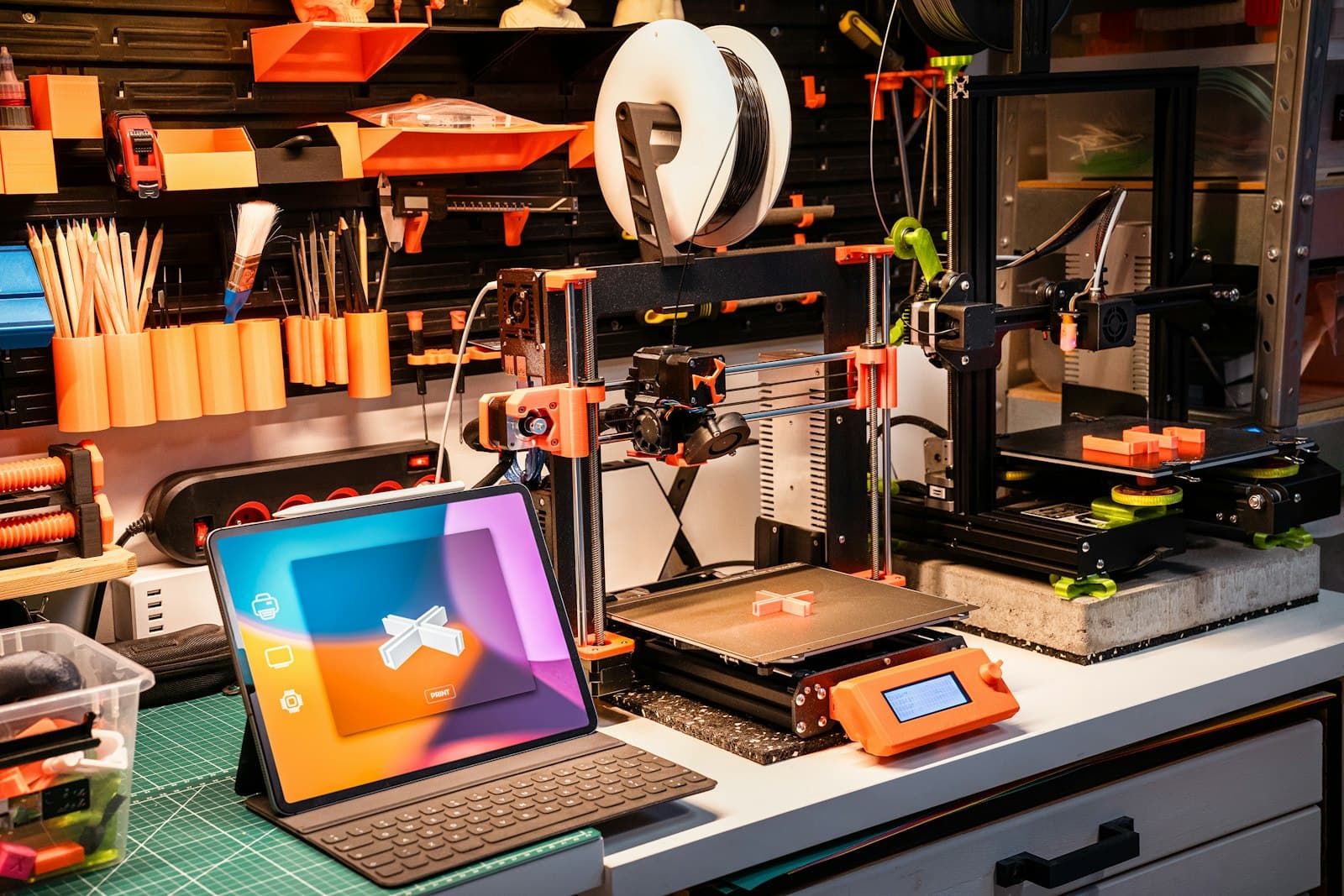 A 3D printer, tools and a laptop on a workbench