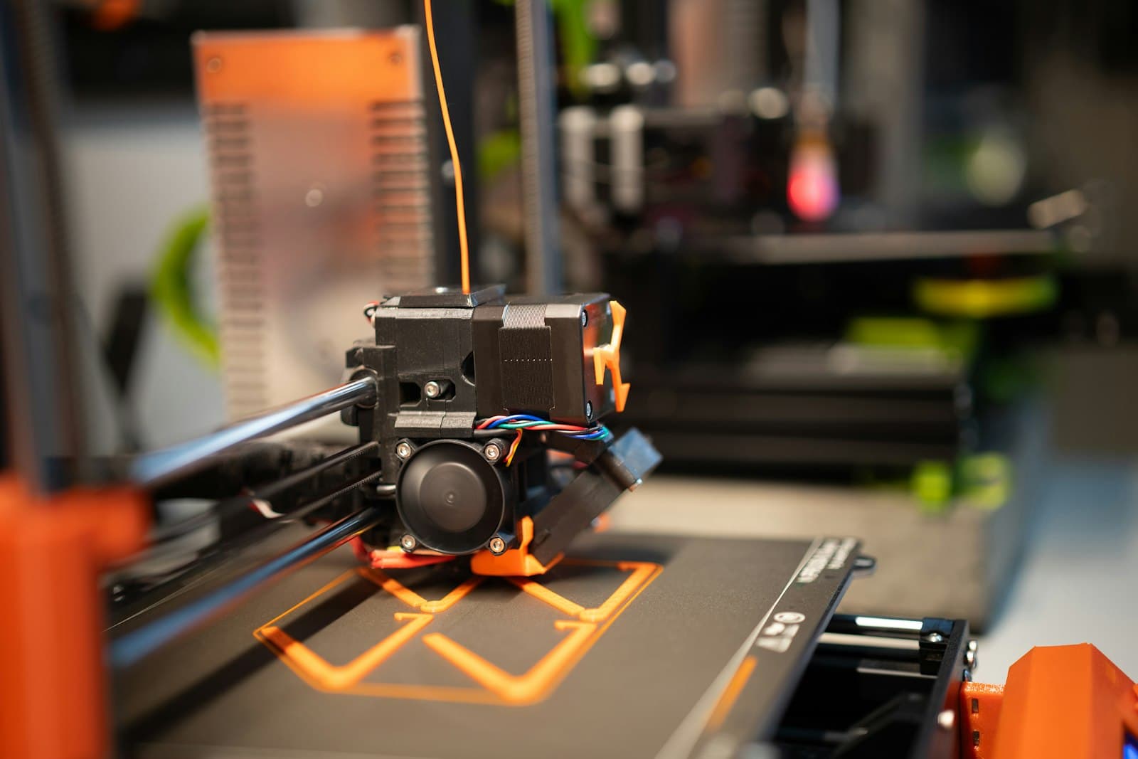 A printhead laying down the first orange layers of a print