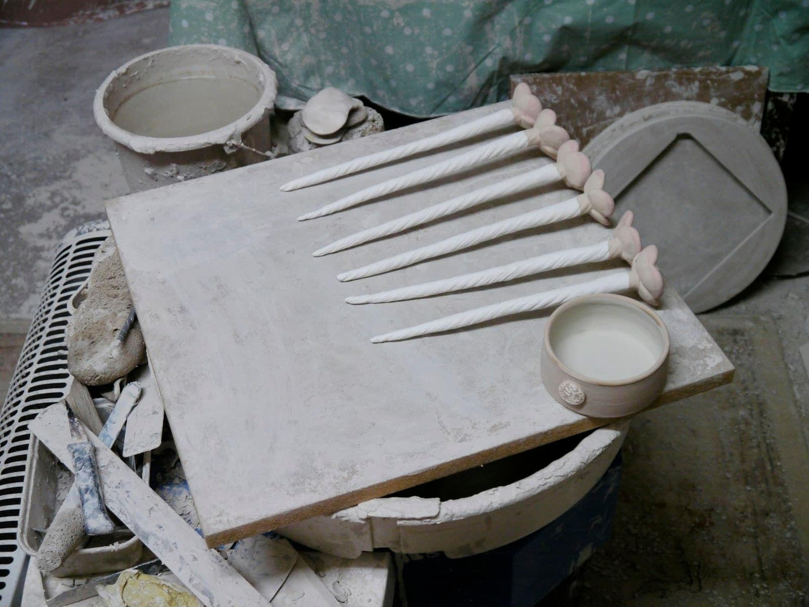 A clay slab and ceramic tools on a dusty board
