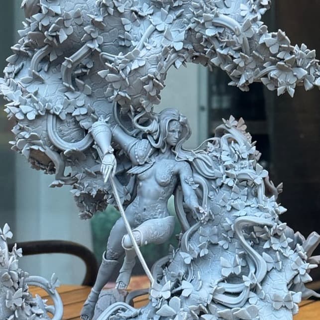 A large unpainted resin diorama of swirling leaves around a figure, on the studio table